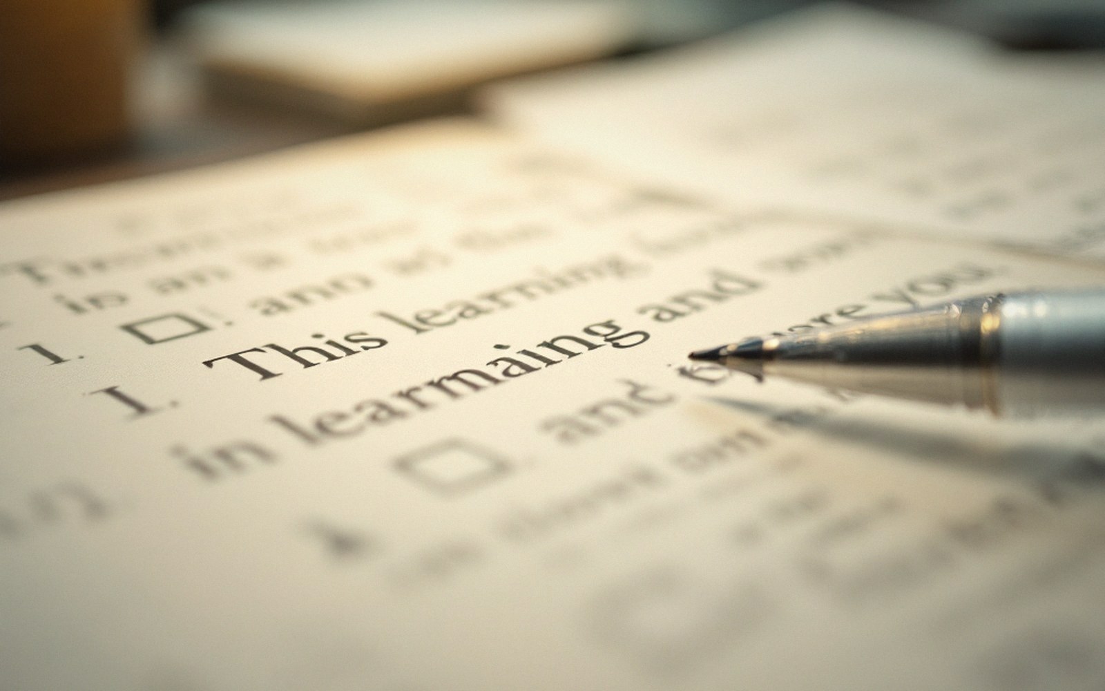 A pen tip resting on a printed page with checkbox items and text about learning