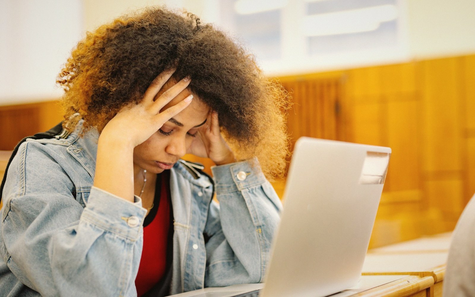 A woman holds her head in frustration while looking at a laptop screen
